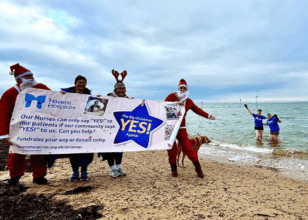 people in santa suit stood on a beach holding a banner