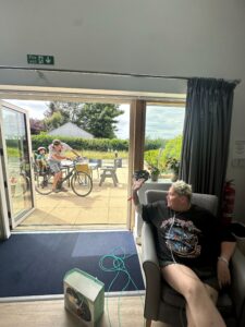 Bex looking at Zu on his bike outside the hospice