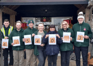 Employees stood outside garden centre holding up numbers for how much they raised