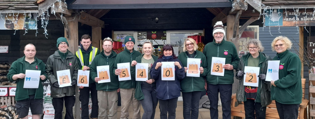 Employees stood outside garden centre holding up numbers for how much they raised