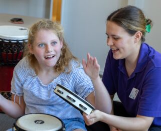 Emily playing instrument with Care Team member Emma