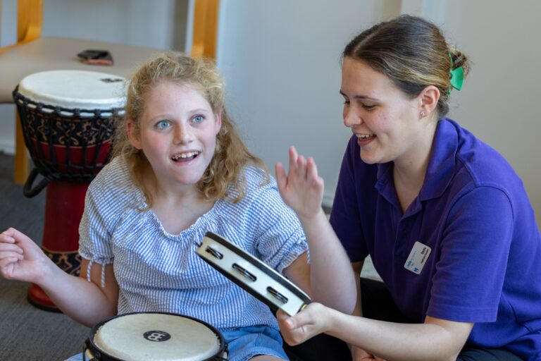 Emily playing instrument with Care Team member Emma