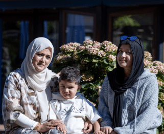 Zak, sat with his mum and sister outside at Little Havens