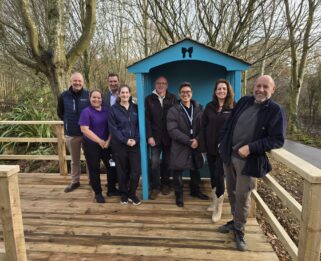 A group of men and women from the Knight Group standing around a new bench with representatives from Havens Hospices.