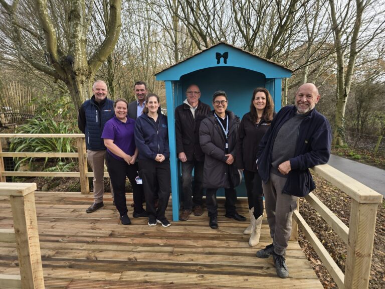 A group of men and women from the Knight Group standing around a new bench with representatives from Havens Hospices.