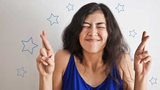 Women with brown hair and smiling with her fingers crossed in the air. Blue stars around the outside