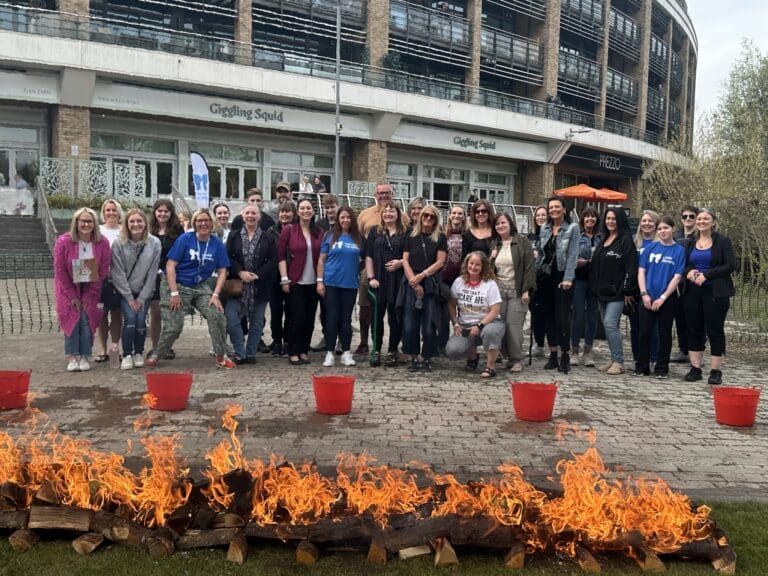 Large group of Fire Walk Supporters standing behind a line of flames in the Bond Street Bowl Chelmsford