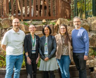 Group of five people stood outside looking at the camera smiling