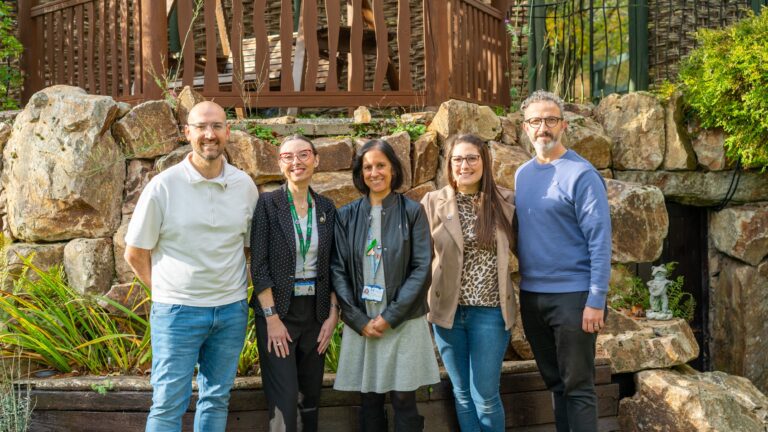Group of five people stood outside looking at the camera smiling