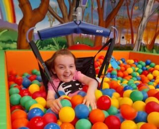 Sophia in a hoist, playing in the ball pit at Little Havens