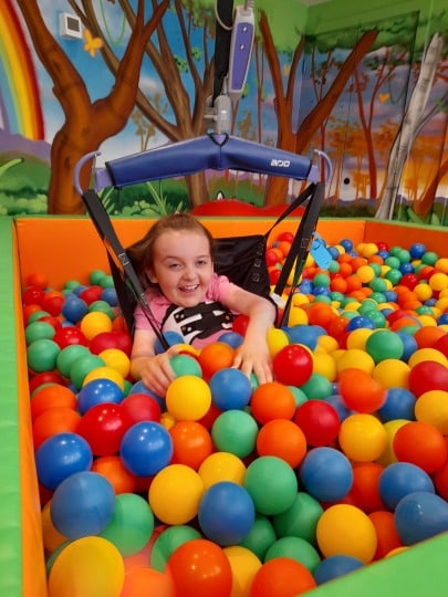 Sophia in a hoist, playing in the ball pit at Little Havens