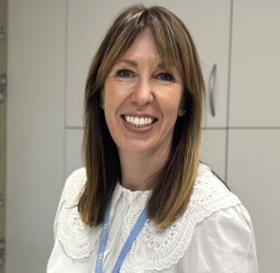 Women with brown hair wearing a white shirt smiling direct to the camera
