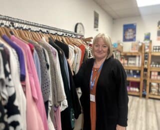 Volunteer Sue standing in front of a clothes rail