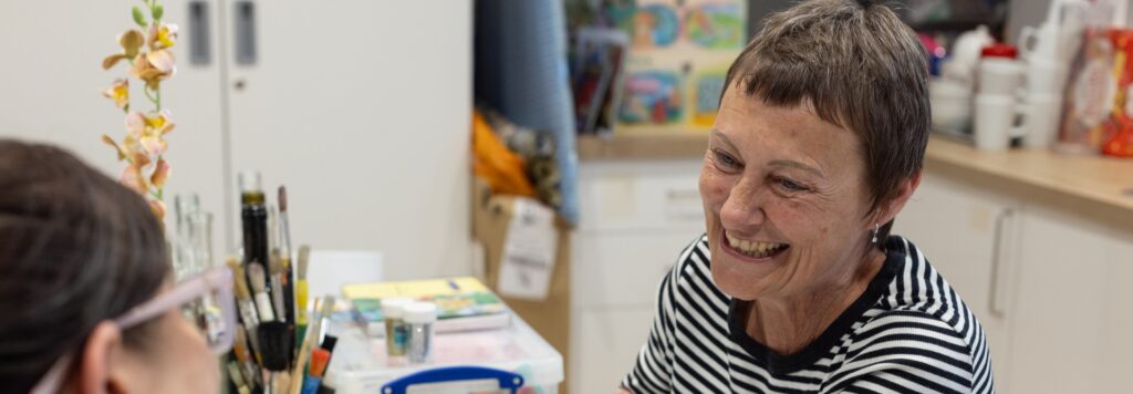 Lady in a striped top smiling and looking at a member of staff