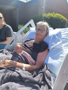 Zara in her bed, holding a glass of wine in the garden at Fair Havens 