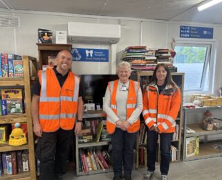 Three representatives from Suez and Havens Hospices in High Vis inside the Reuse Shop