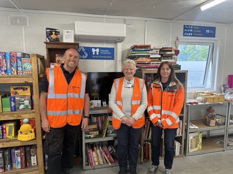 Three representatives from Suez and Havens Hospices in High Vis inside the Reuse Shop