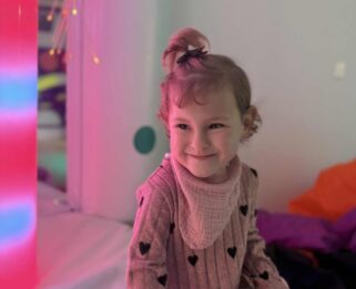 Aliyah sat in the sensory room with lights behind her