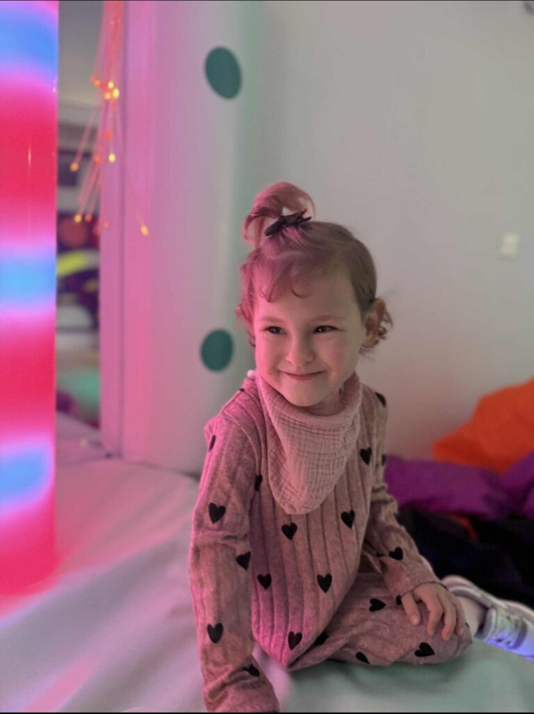 Aliyah sat in the sensory room with lights behind her