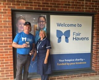 Man in a Havens Hospices top infront of the Fair Havens sign with a nurse.
