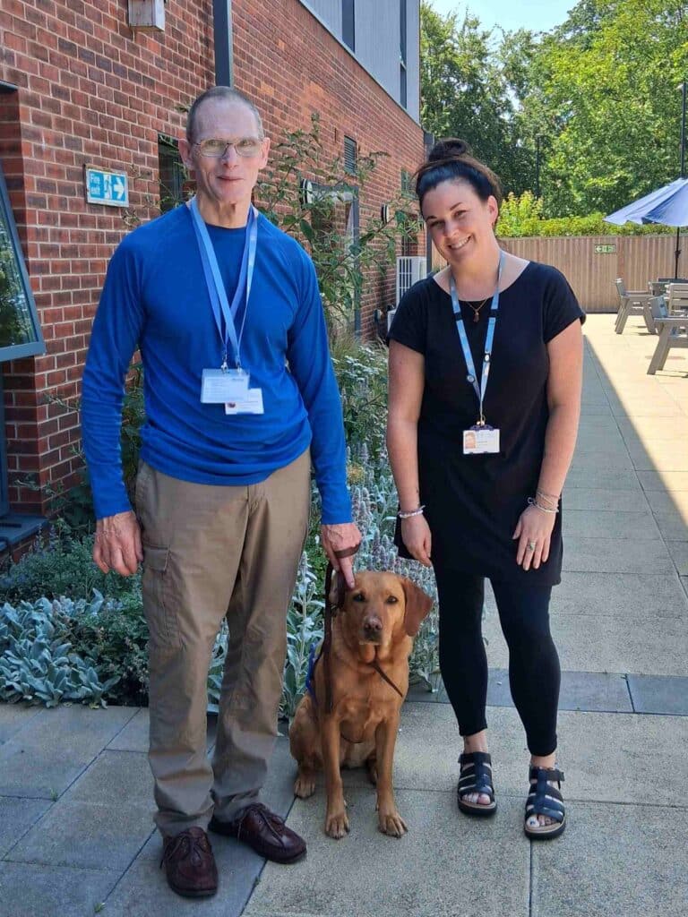 Andrew standing in Fair Haven's garden holding his dog's, Rosa, lead next to Lizzie