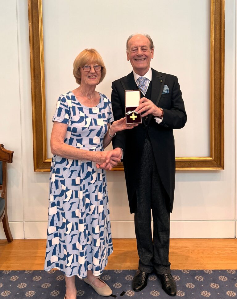 Bobbie Nichols shaking hands with Lord Lingfield, President of the League of Mercy, and holding order of mercy award medal