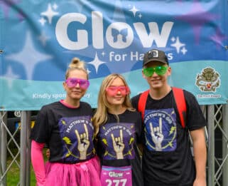 Two women and a man in glowing outfits.
