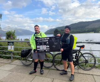 Two men standing in front of a lake with bikes.