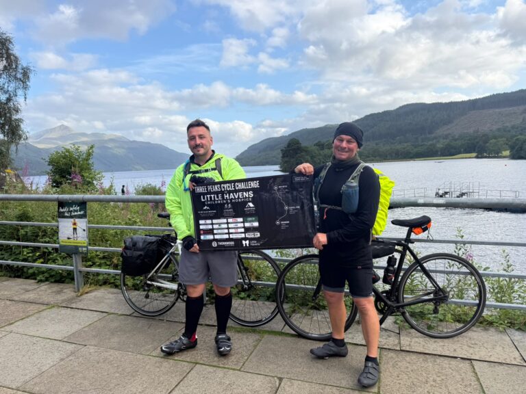 Two men standing in front of a lake with bikes.