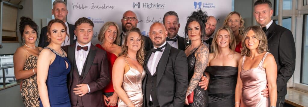 A team in black tie attire pose for a photo