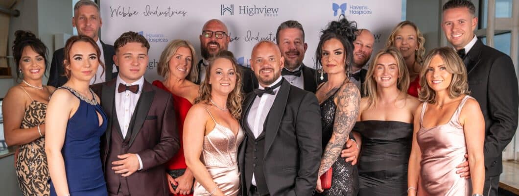A team in black tie attire pose for a photo