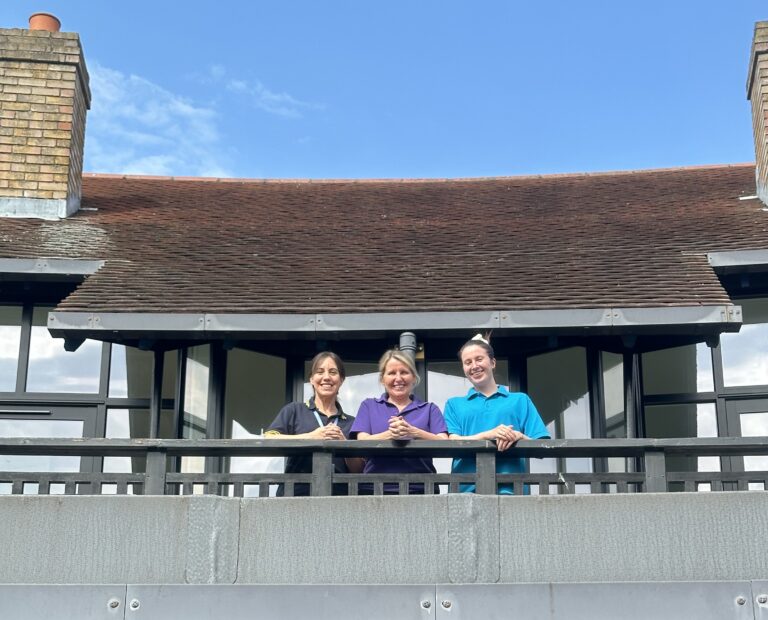 Three Care Team members on the balcony at Little Havens in front of newly renovated windows