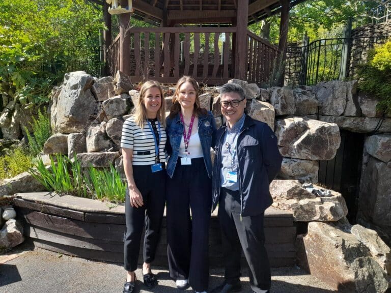 Two women and a man standing in the Little Havens garden smiling