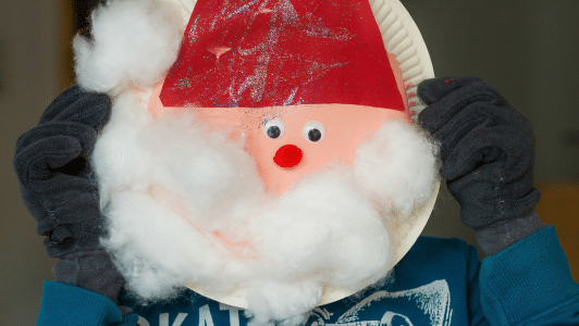 Child hands holding up a paper plate with santa decorated