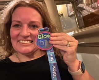 A lady smiling with a Glow for Havens medal
