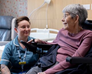 Healthcare Assistant looking at patient sitting in a wheelchair on the inpatient unit at Fair Havens
