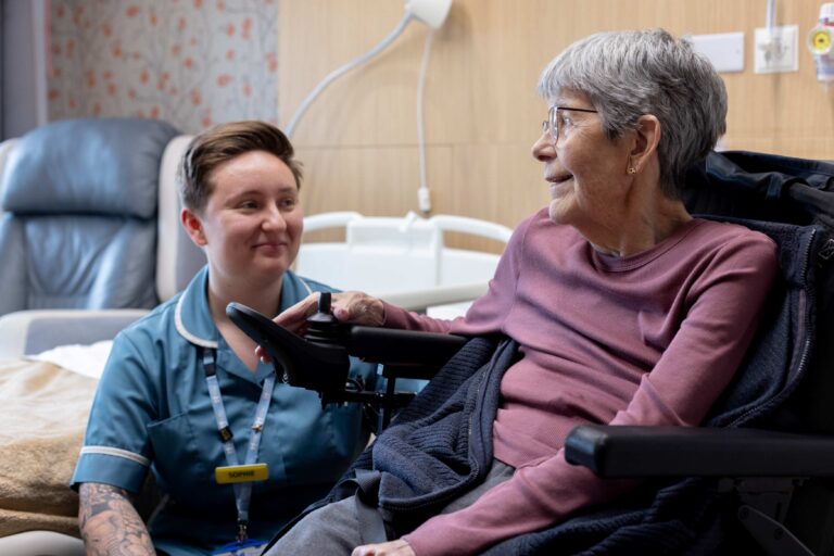 Healthcare Assistant looking at patient sitting in a wheelchair on the inpatient unit at Fair Havens